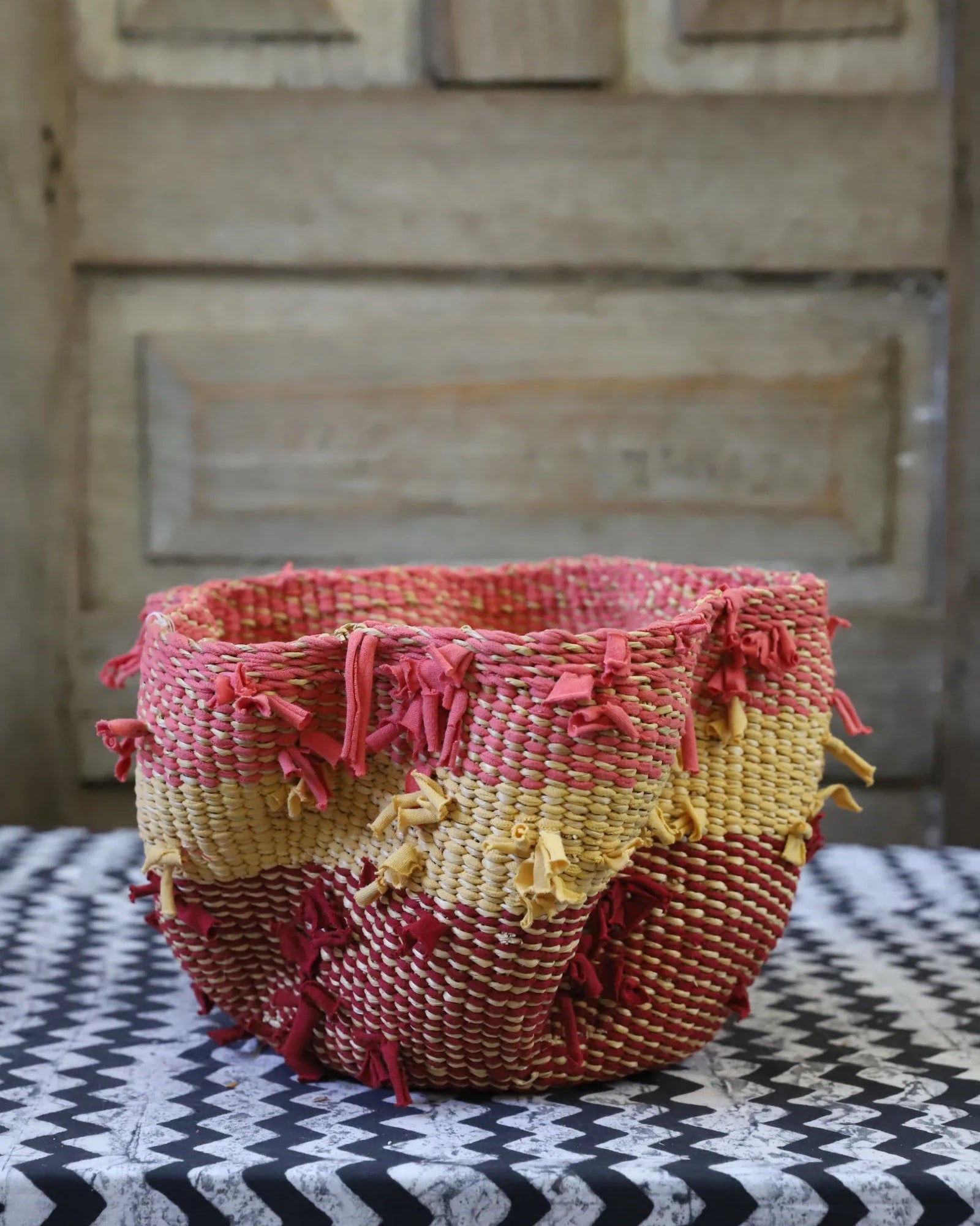 Colourful basket sitting on black and white cloth in front of a wooden door