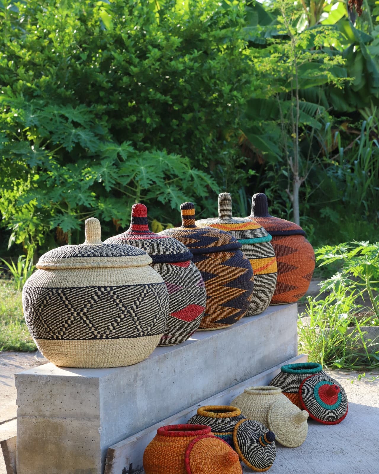 Multiple coloured baskets sitting on concrete with green foliage in the background