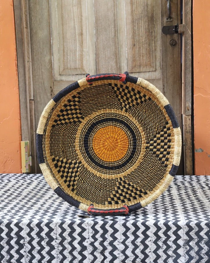 Woven basket on a table with black and white cloth a wooden door in the background