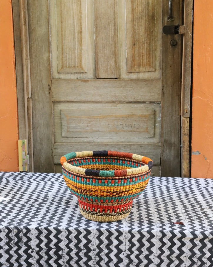 Woven storage basket with a beautiful pattern on a black and white cloth against a wooden door.
