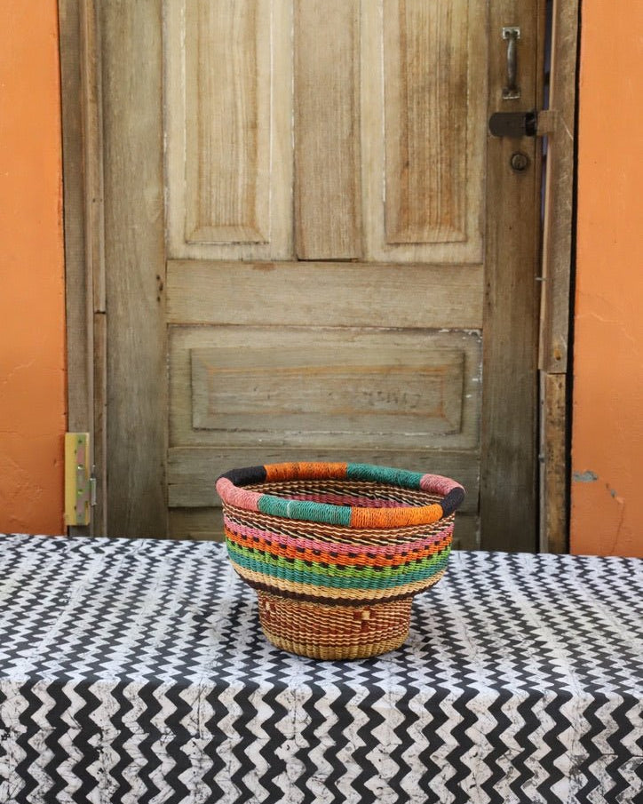 Woven storage basket with a beautiful pattern on a black and white cloth against a wooden door.