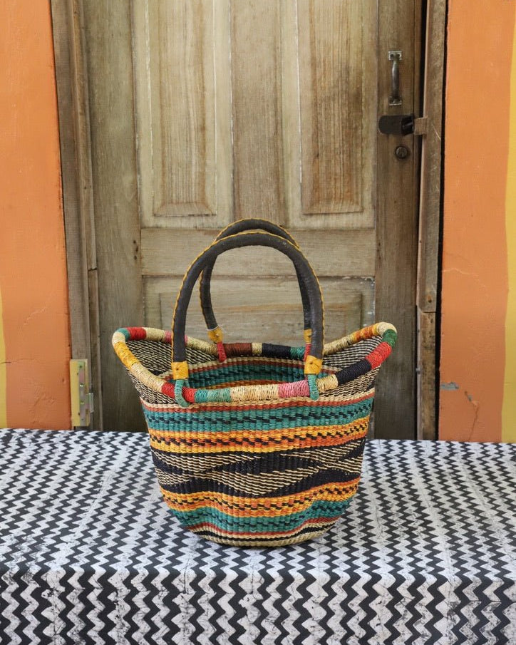 Woven carry on basket with premium leather on a black and white cloth against a wooden door