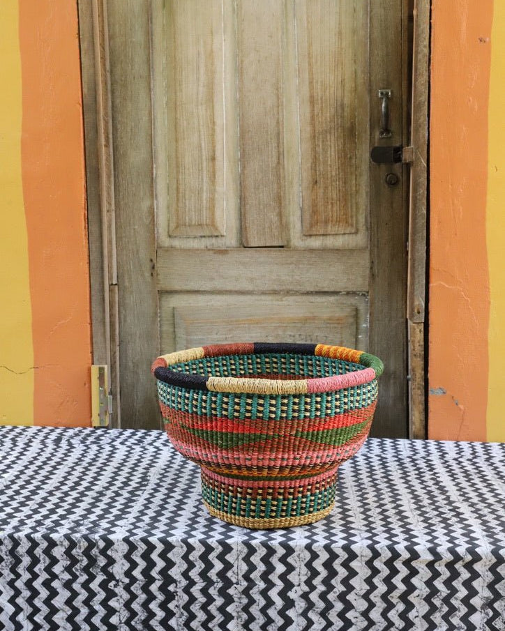 Woven storage basket with a beautiful pattern on a black and white cloth against a wooden door.