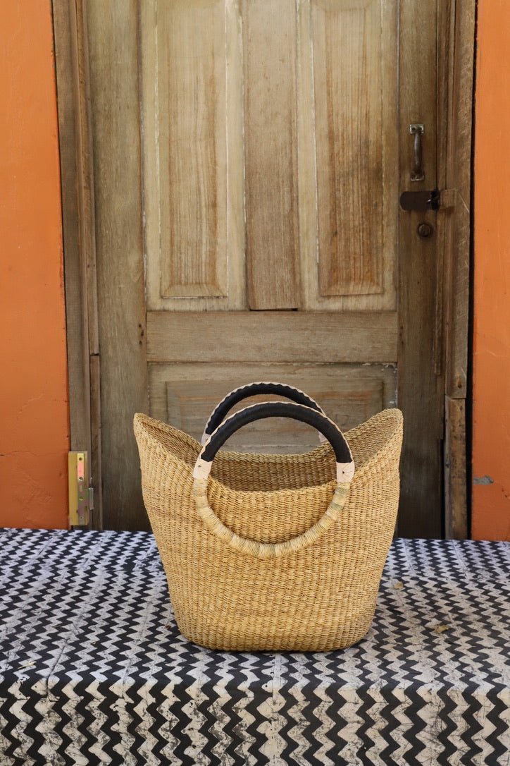 Woven handbag on a patterned surface with a wooden door in the background