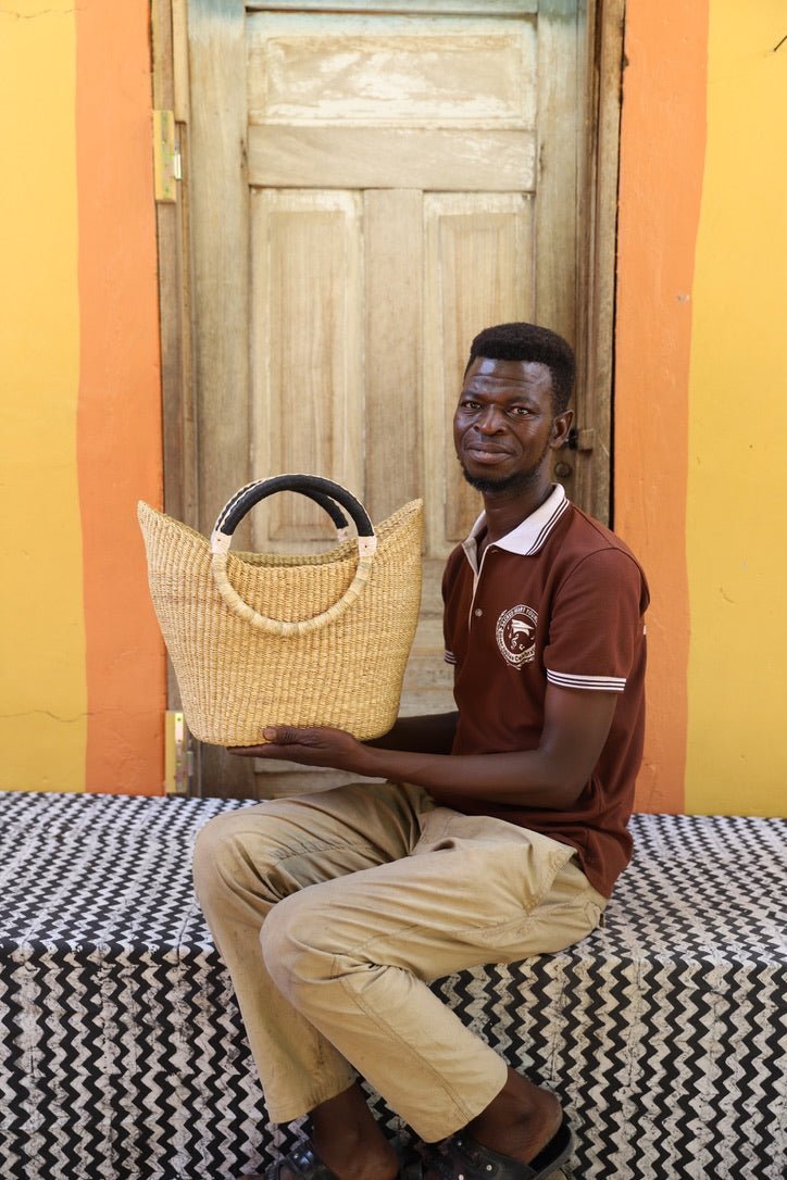 Man holding a woven basket against a colorful wall.