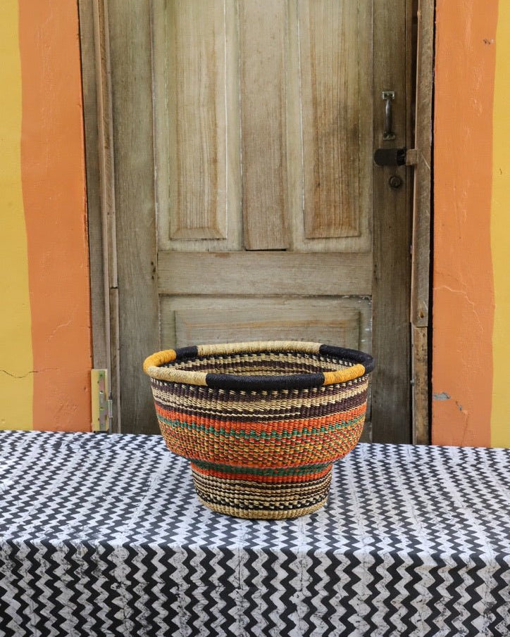 Woven storage basket with a beautiful pattern on a black and white cloth against a wooden door.
