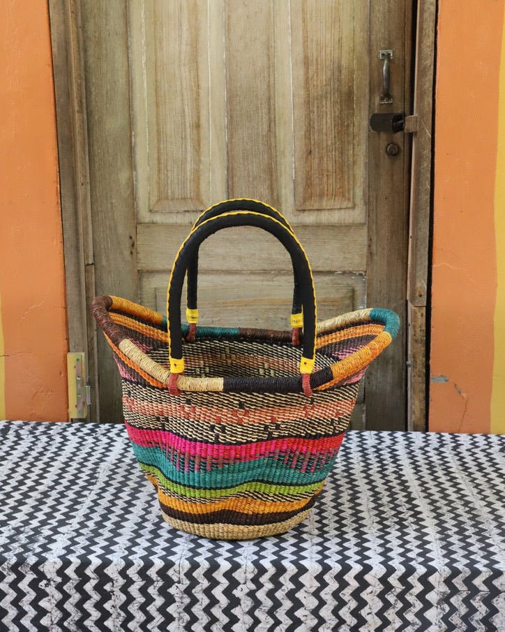 Woven carry on basket with premium leather on a black and white cloth against a wooden door
