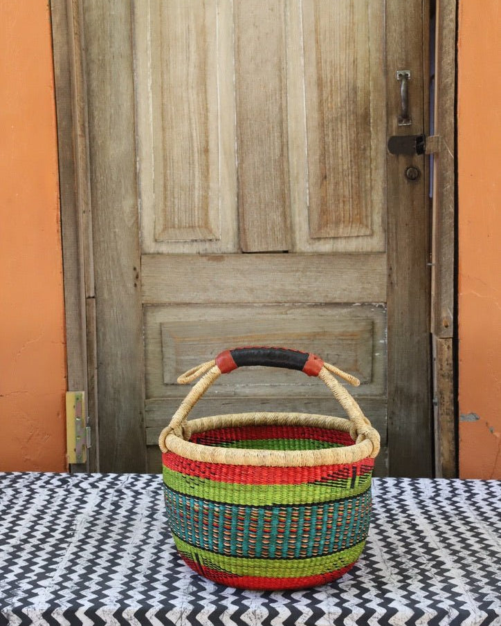 Woven carry on bag with premium leather handles on a black and white cloth against a wooden door.
