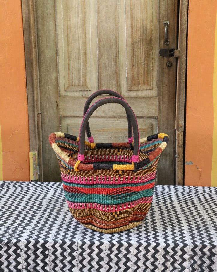 Woven carry on basket with premium leather on a black and white cloth against a wooden door