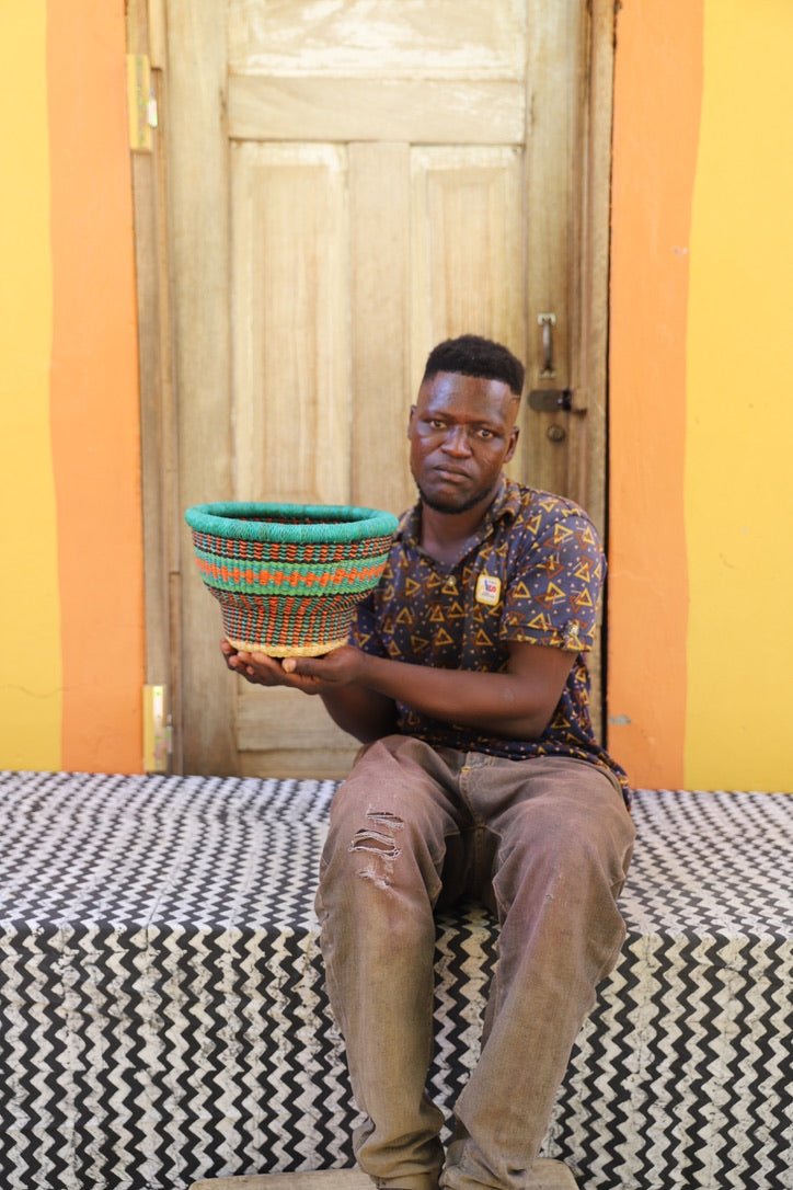 Man holding a colorful woven basket in a room with patterned walls .
