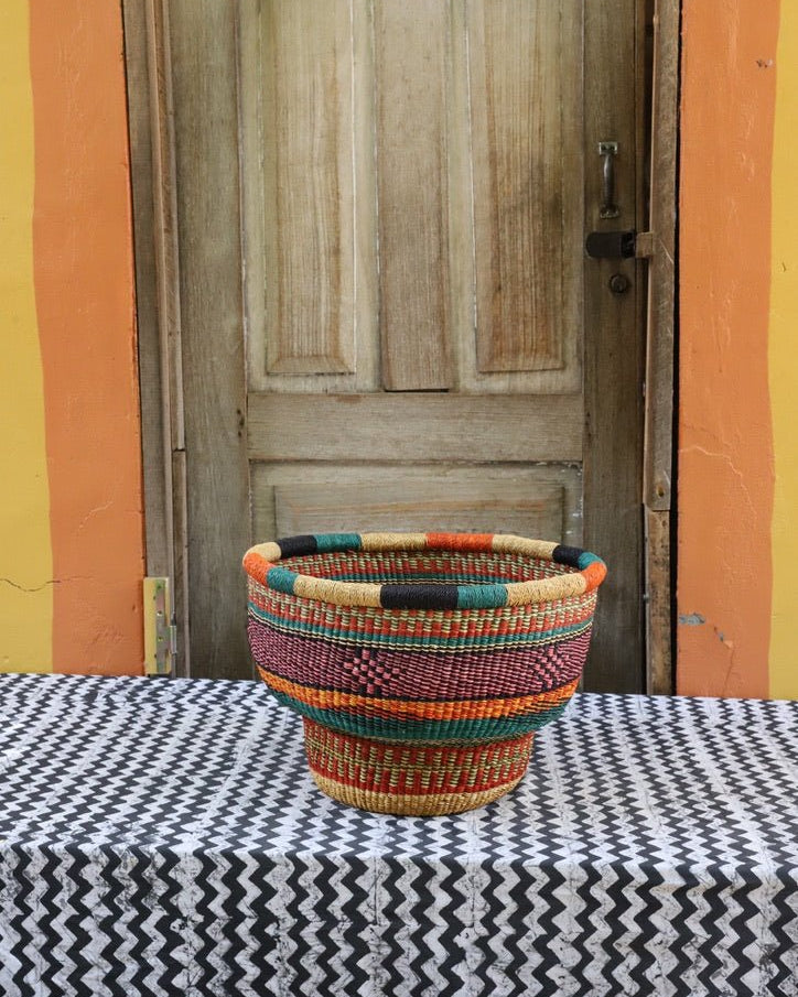 Colorful woven basket on a table with a wooden door and colorful wall in the background