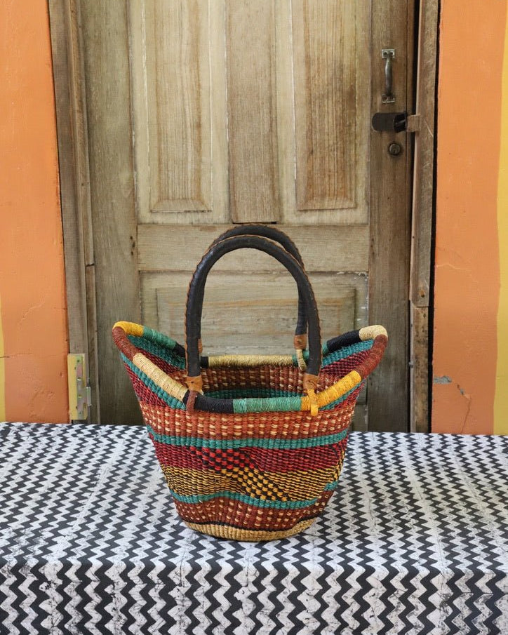 Woven carry on basket with premium leather on a black and white cloth against a wooden door