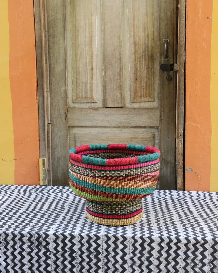 Woven storage basket with a beautiful pattern on a black and white cloth against a wooden door.