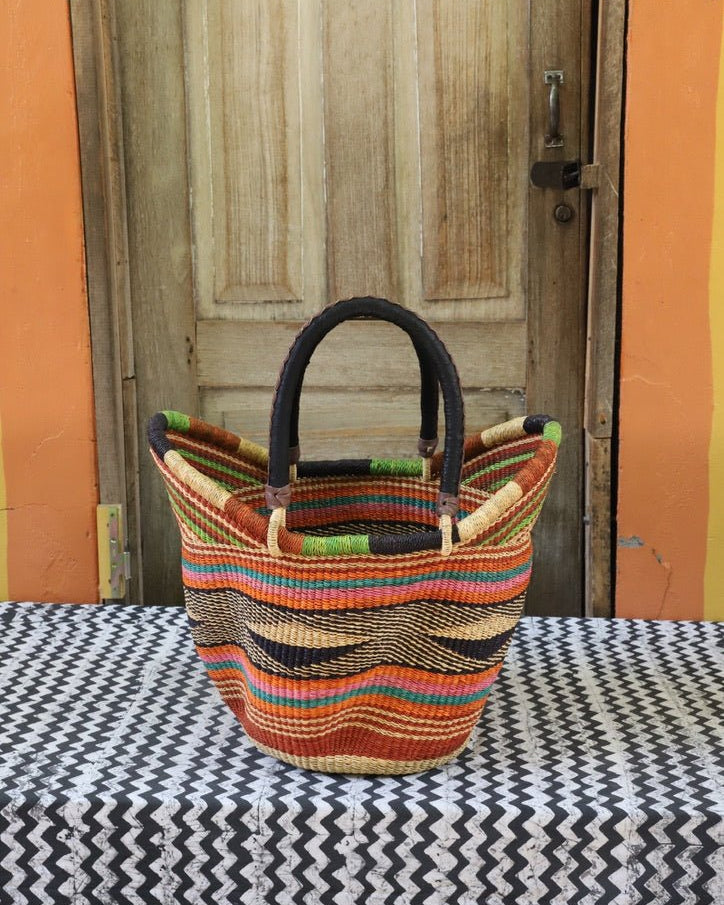 Woven carry on basket with premium leather on a black and white cloth against a wooden door