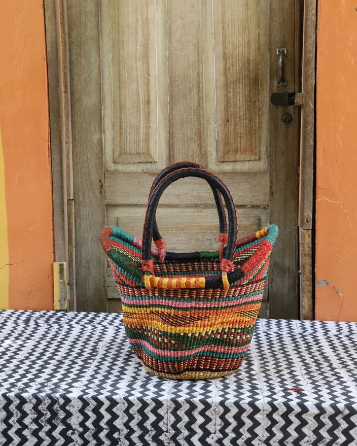 Woven carry on basket with premium leather on a black and white cloth against a wooden door