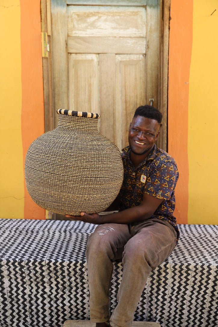 Man holding a large woven basket against a colorful wall.