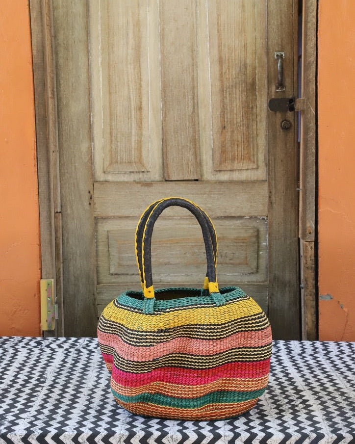 Woven carry on basket with premium leather on a black and white cloth against a wooden door