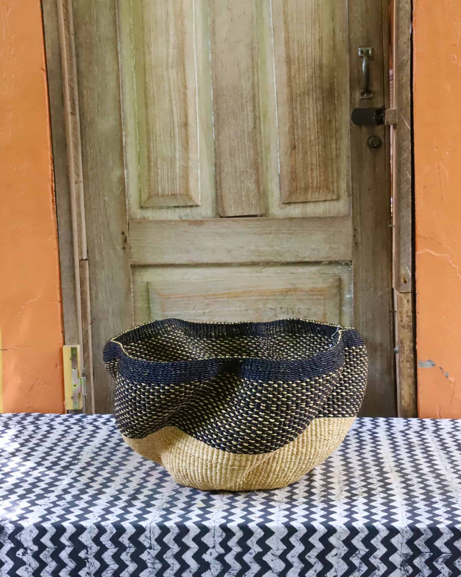 Decorative woven basket on a black and white cloth against a wooden door.