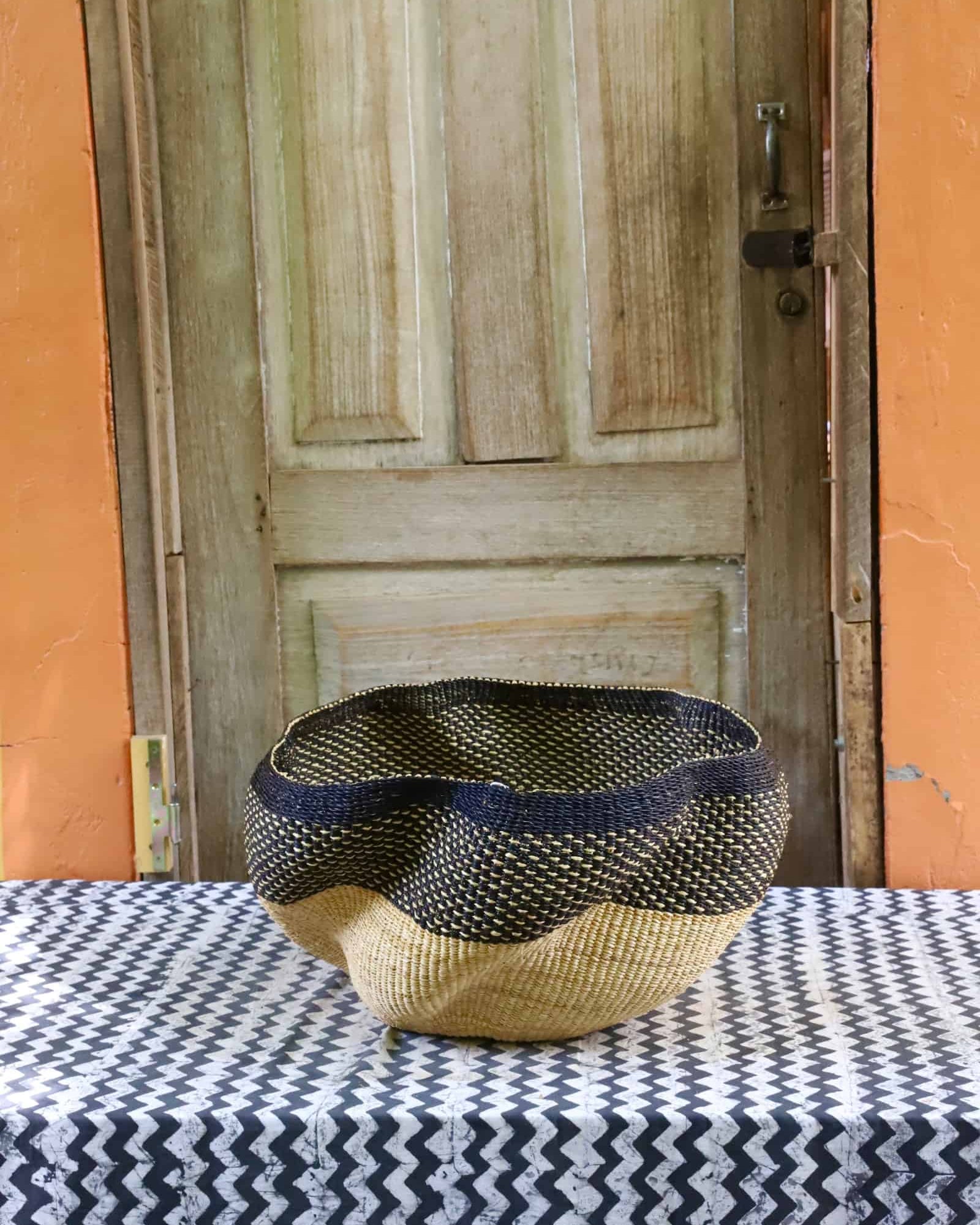 Decorative woven basket on a black and white cloth against a wooden door.