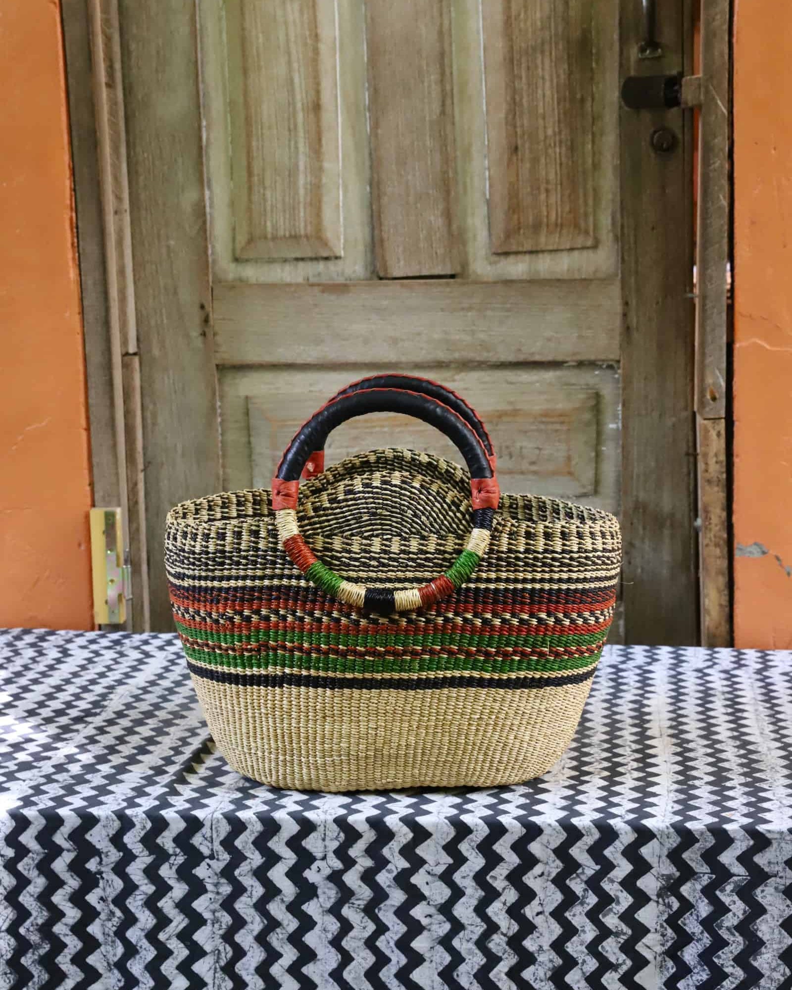 Colorful woven carry on bag on a black and white cloth against a wooden door.