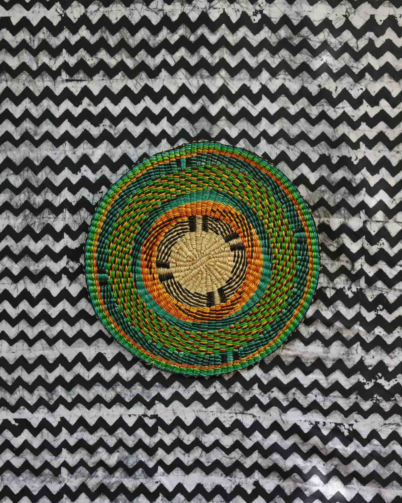 Large woven placemat with teal outer ring, amber inner band and natural straw centre
