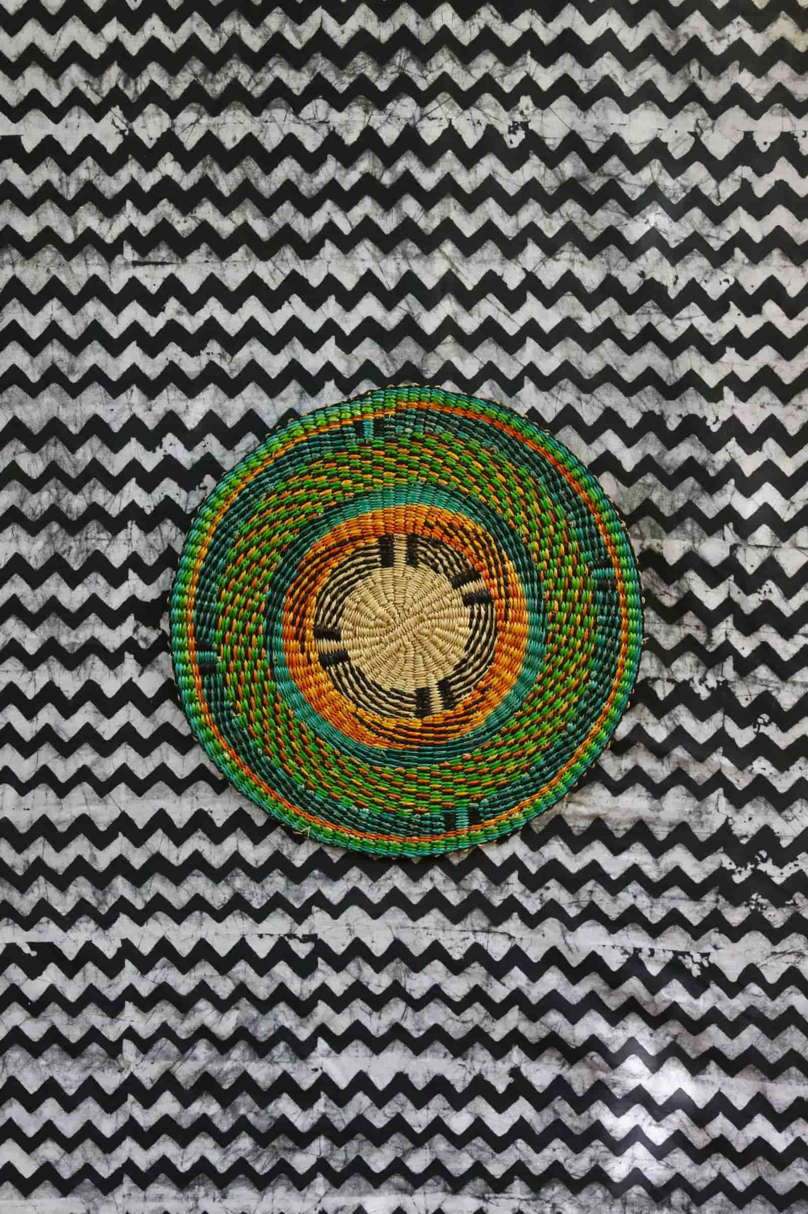 Large woven placemat with teal outer ring, amber inner band and natural straw centre