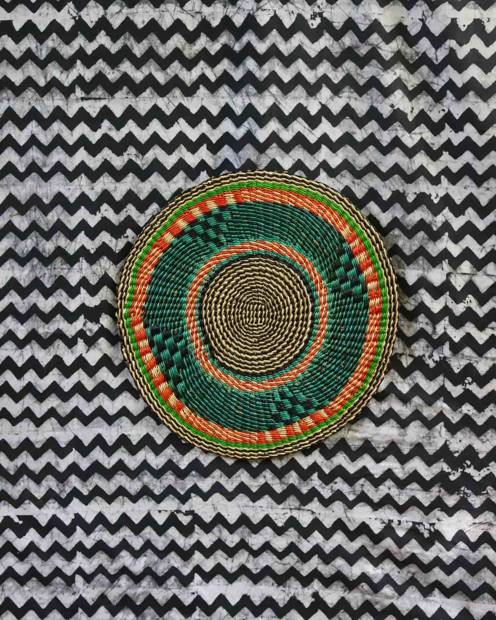 Large woven placemat in forest green with orange accent ring and natural straw border