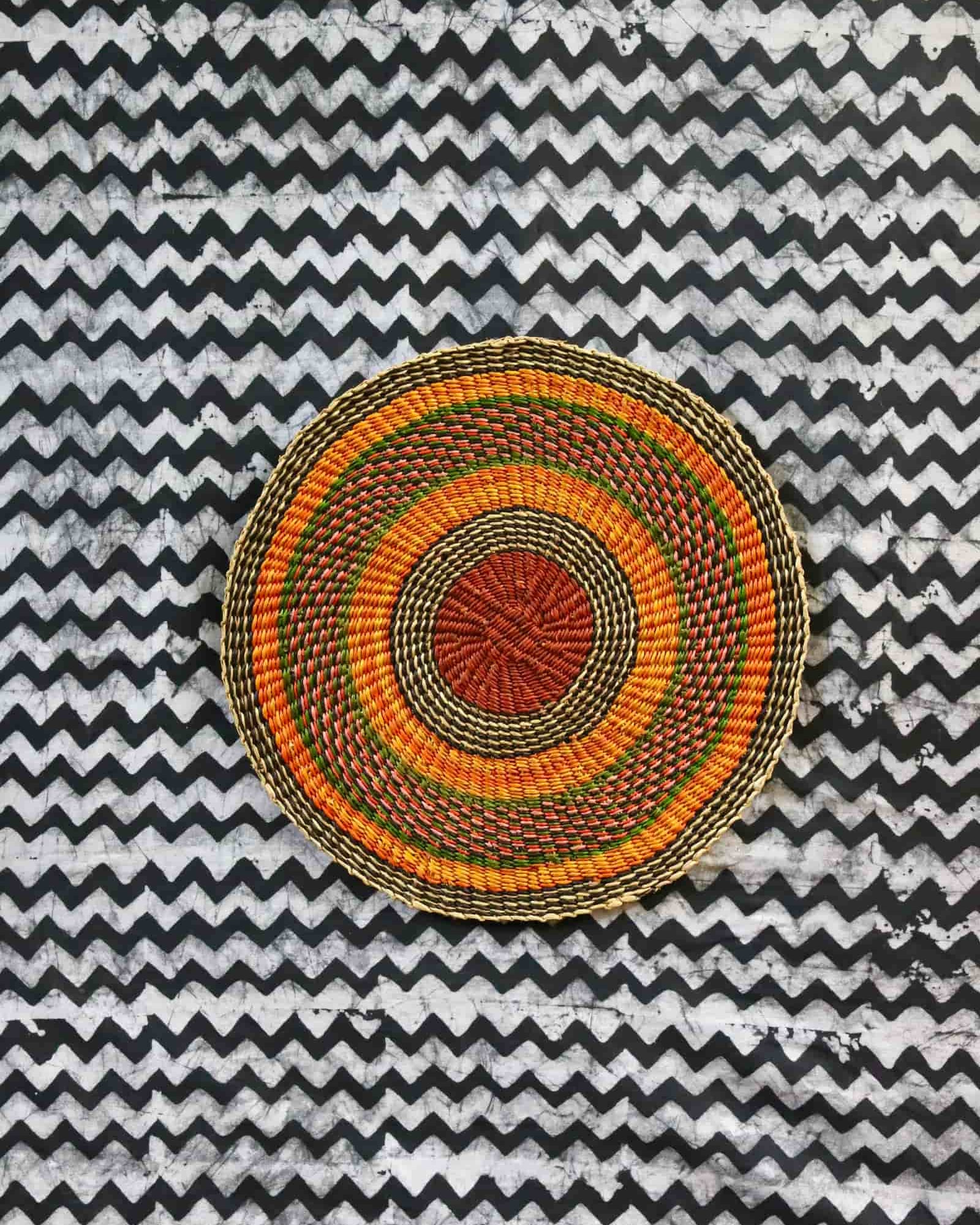 Large woven placemat with terracotta, orange, green and olive concentric bands