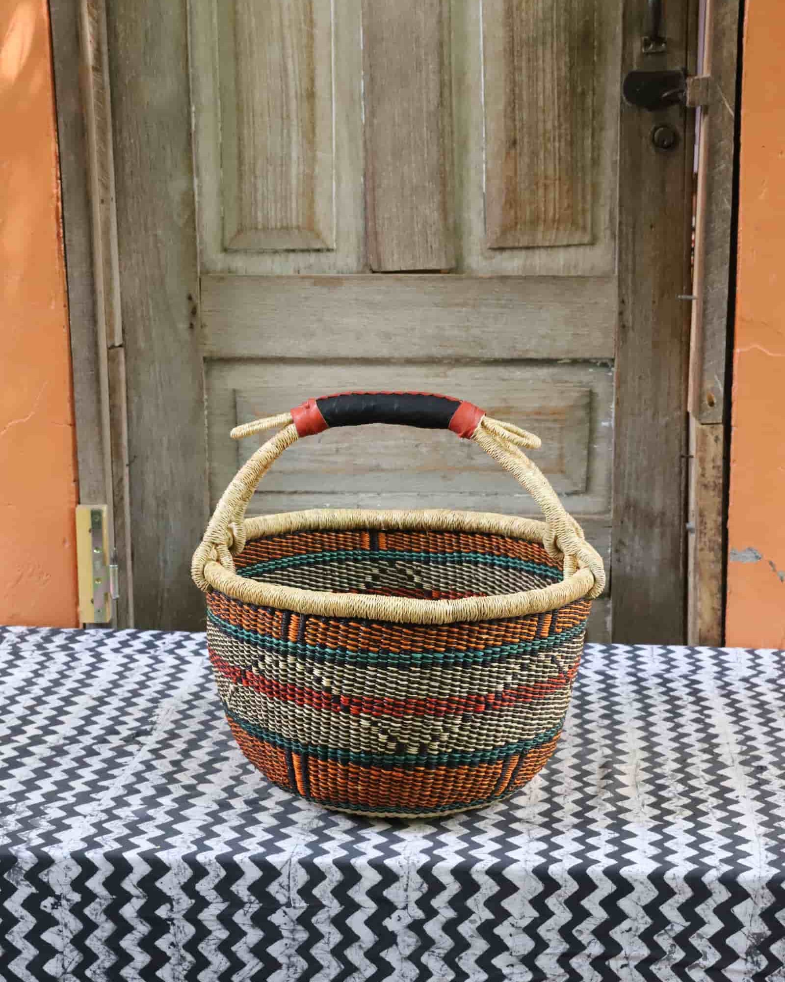 Large round Bolga basket in teal, red, orange and natural diamond pattern with a leather handle