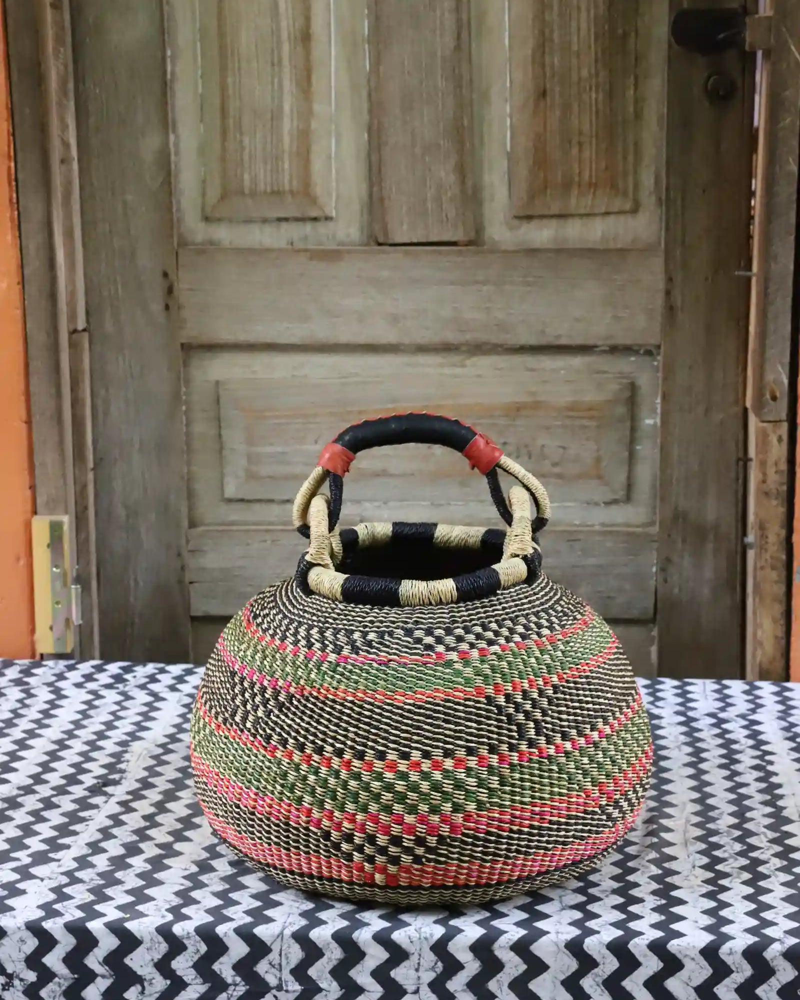 Large pot storage basket in natural straw with green, black and coral woven diagonal stripes
