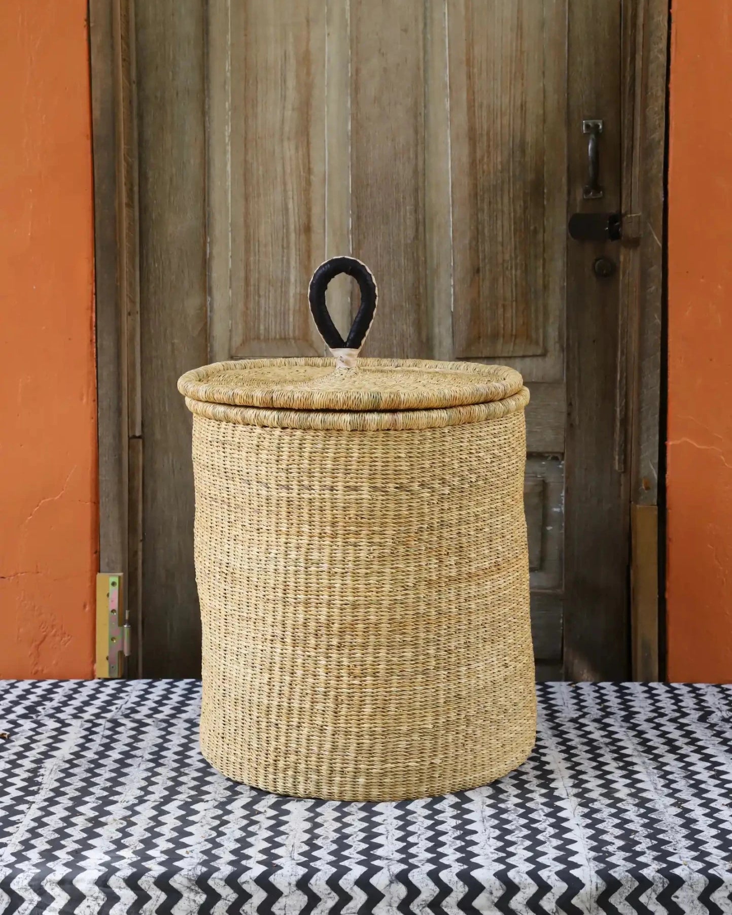 Lidded Laundry Basket with coil (Medium) by The Baba Tree. Handwoven elephant grass with leather handle. Premium Bolgatanga artisan decor.