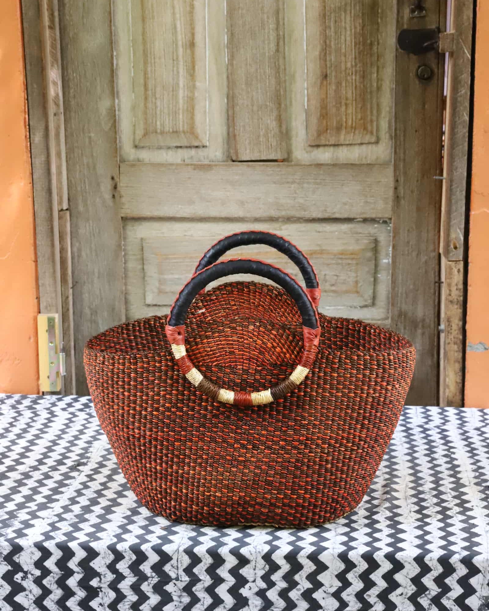 Naughty George weekend bag in deep rust with dark leather handles and gold banding