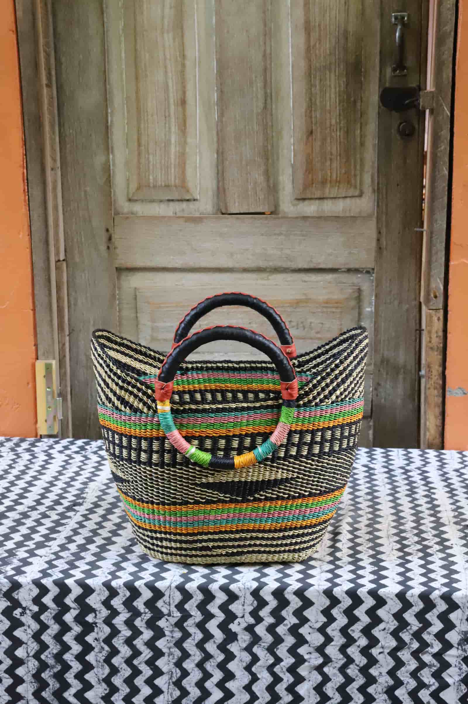 Woven beach bag in black and natural weave with colourful stripe accents and circular leather handles