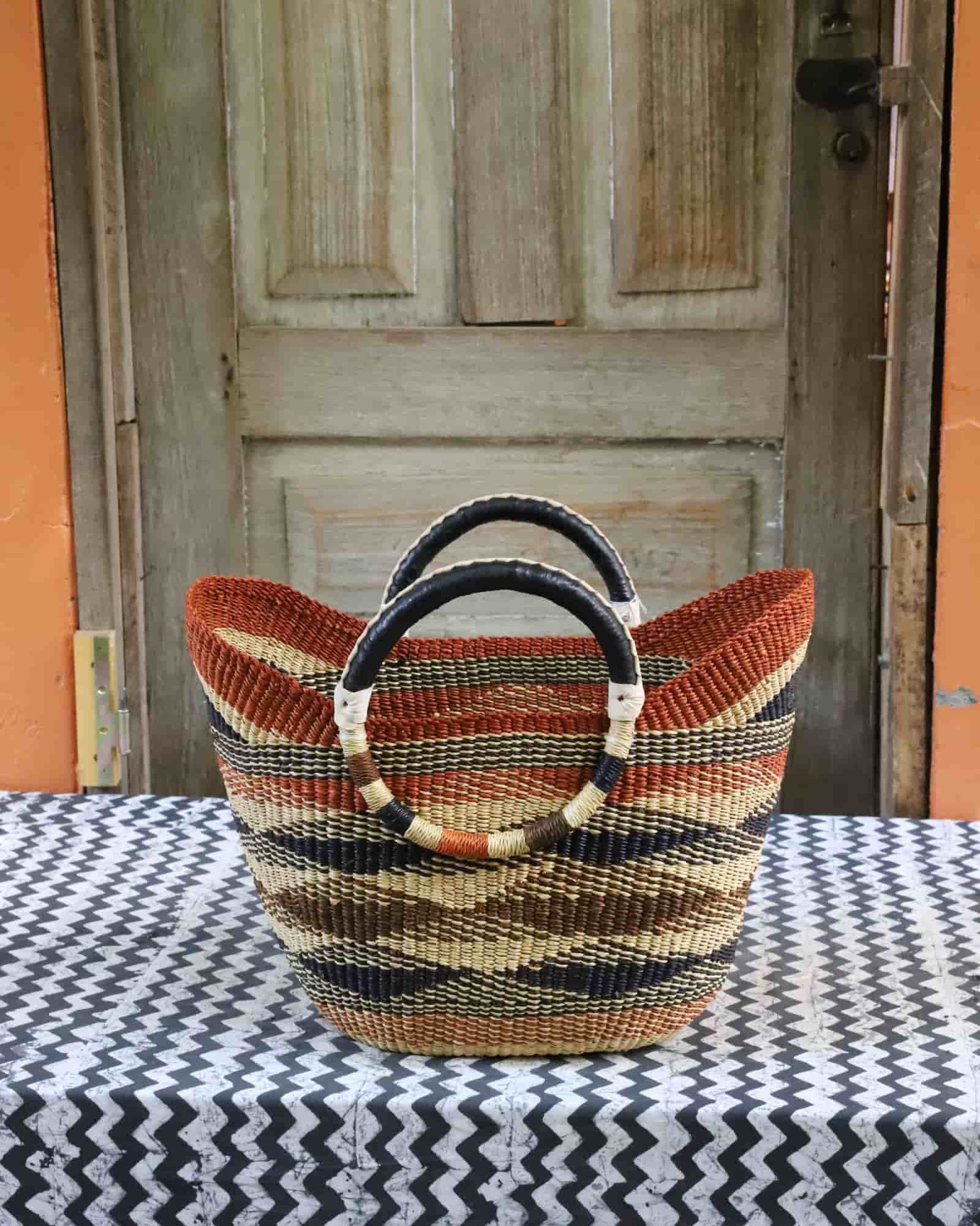 Woven beach bag in terracotta, brown and natural diagonal stripes with circular leather handles