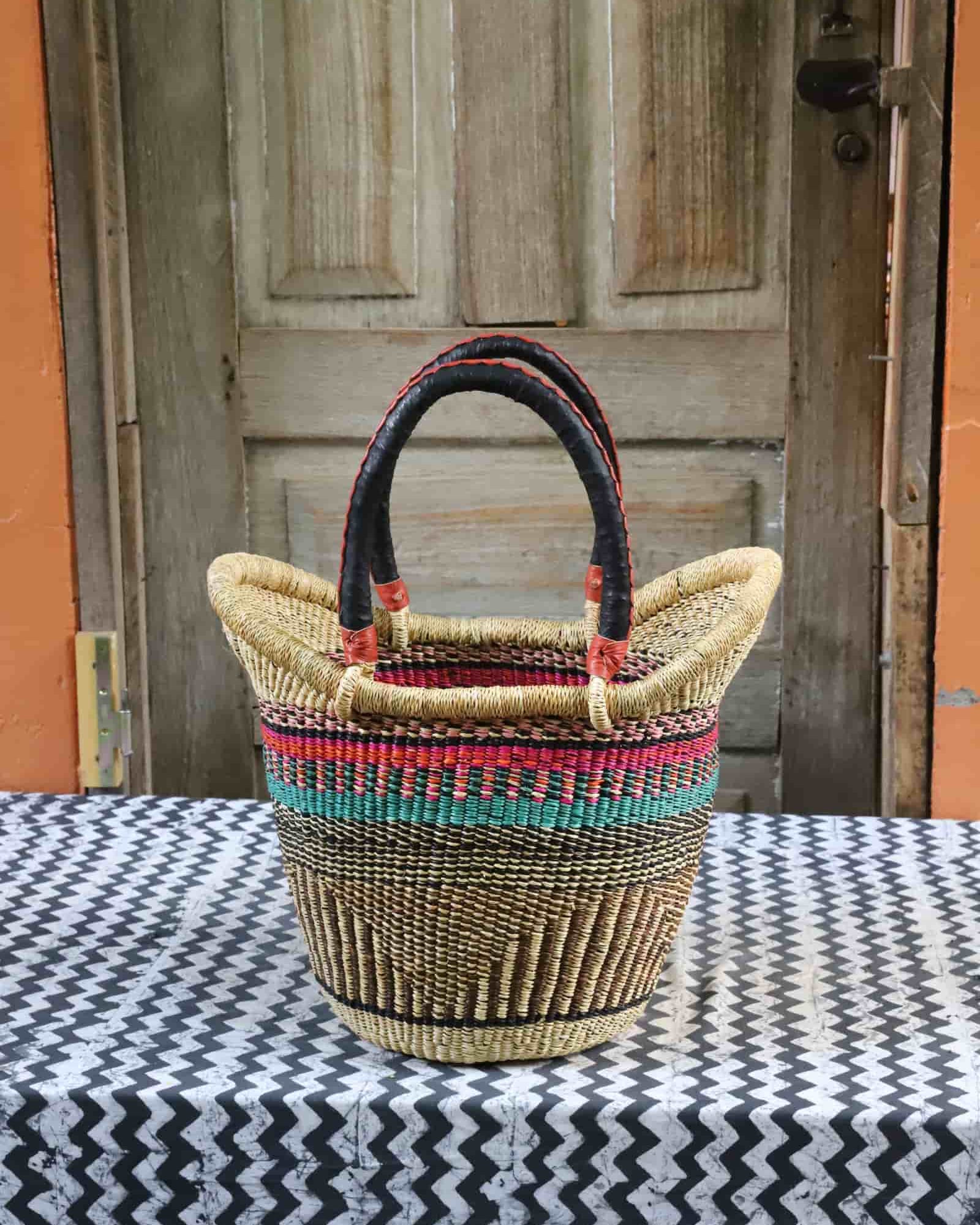 Nyariga shopping basket in natural straw with pink and teal stripe band, dark leather loop handles