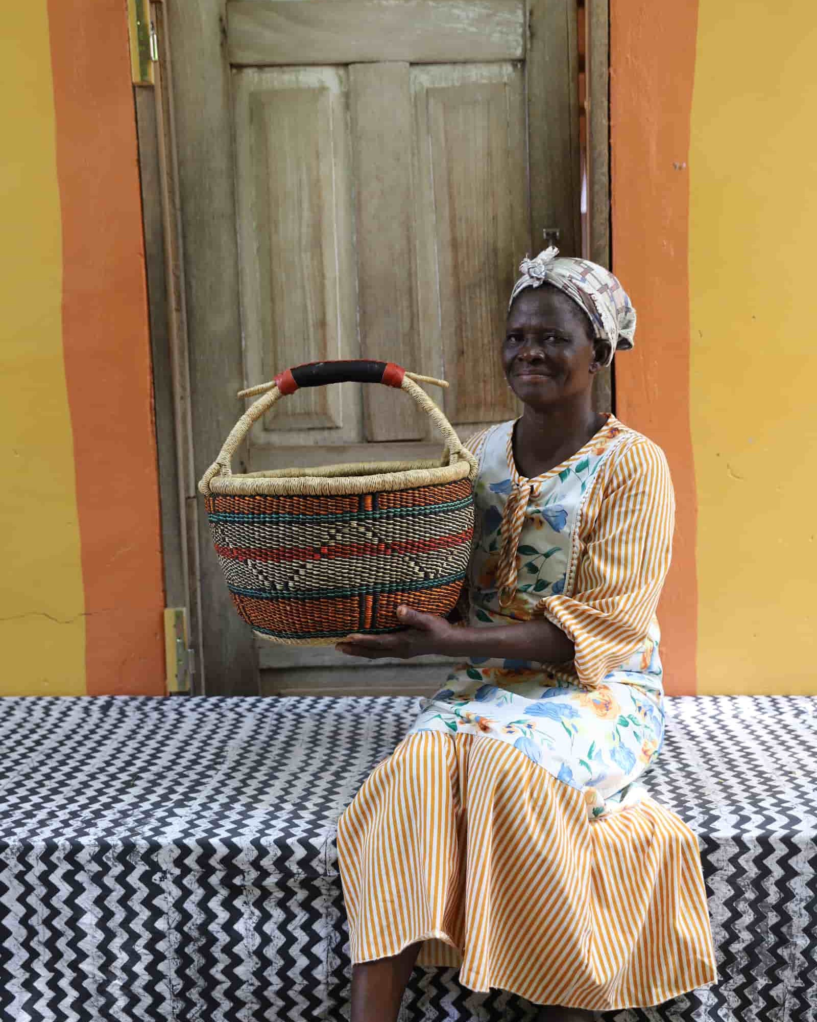 Woman in yellow striped dress holding a large teal and terracotta patterned Bolga shopping basket