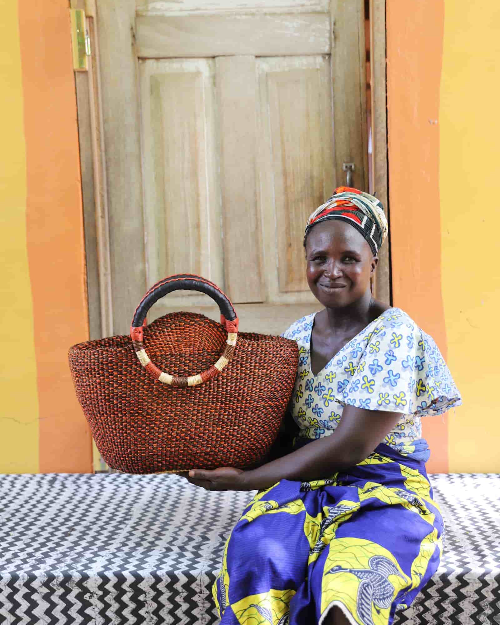 Woman holding Naughty George weekend bag in deep rust, showing scale and round handles