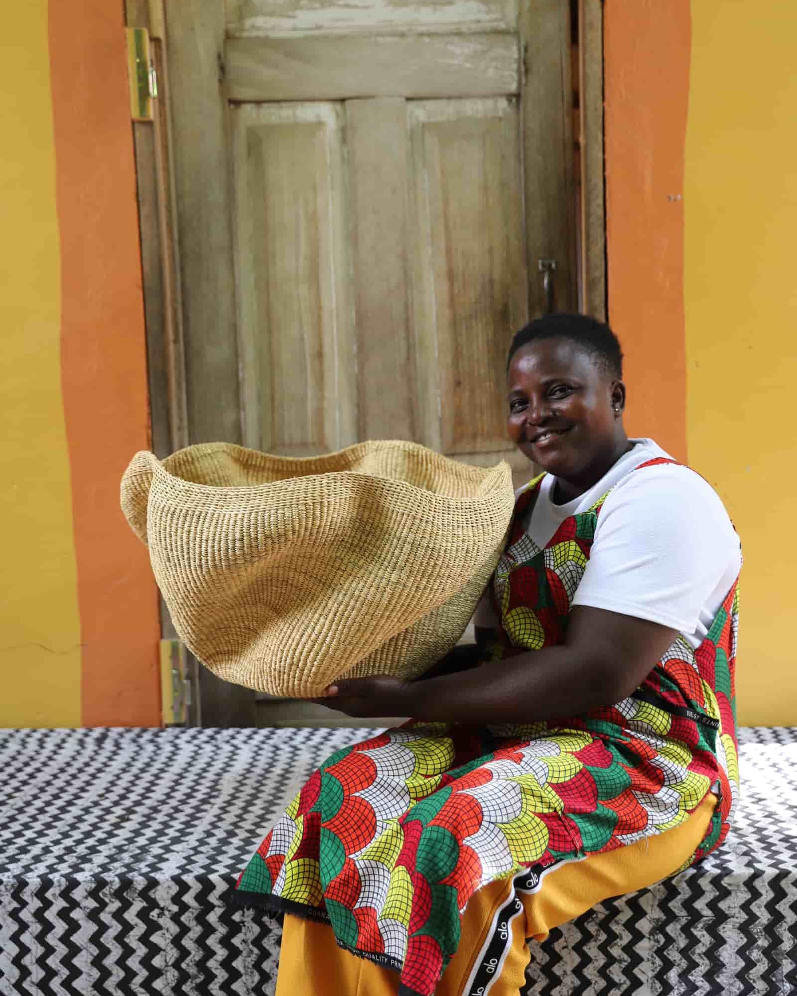 Woman holding large Pakurigo Wave Décor Basket in plain natural straw with undulating wave rim