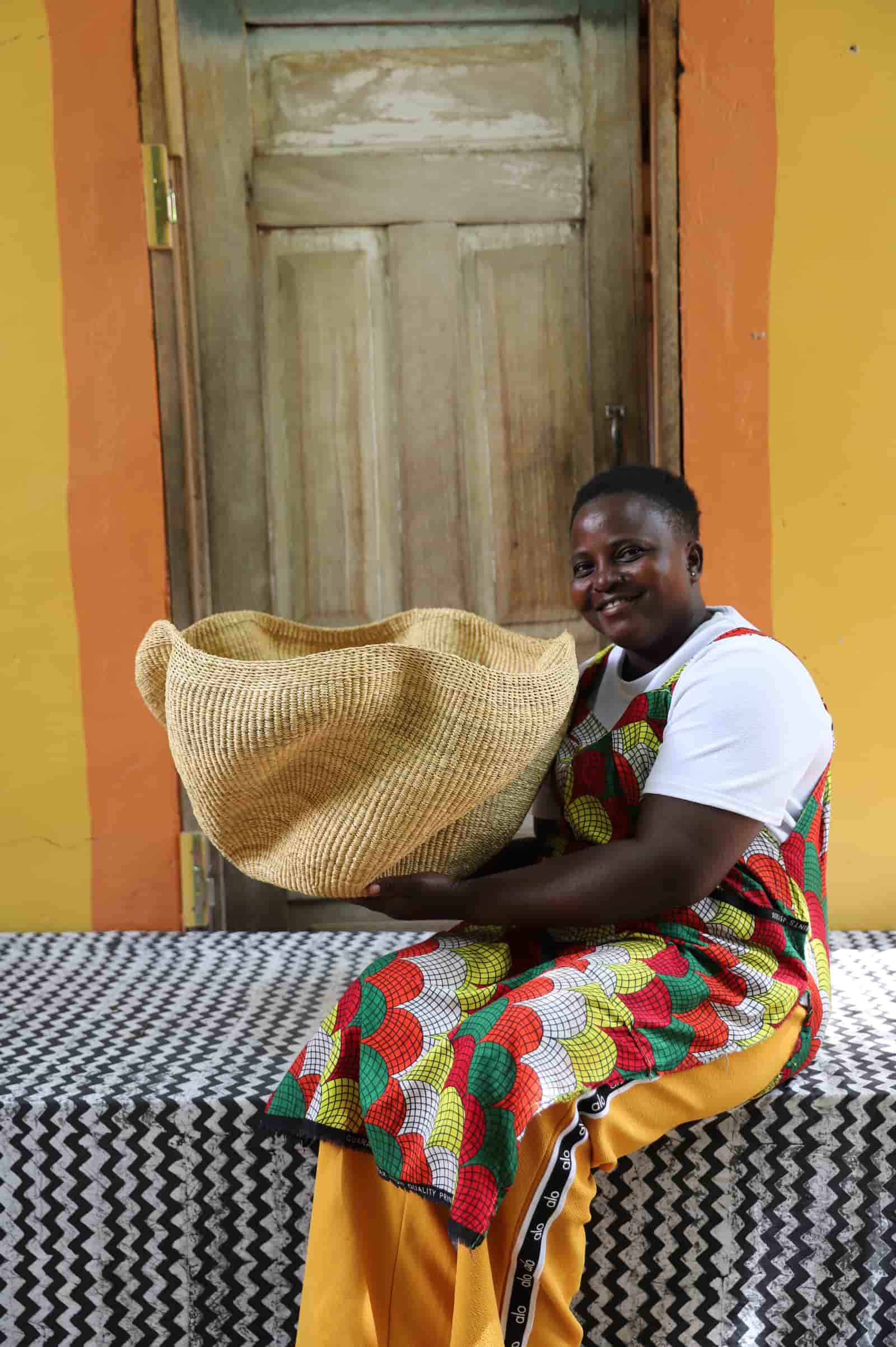 Woman holding large Pakurigo Wave Décor Basket in plain natural straw with undulating wave rim