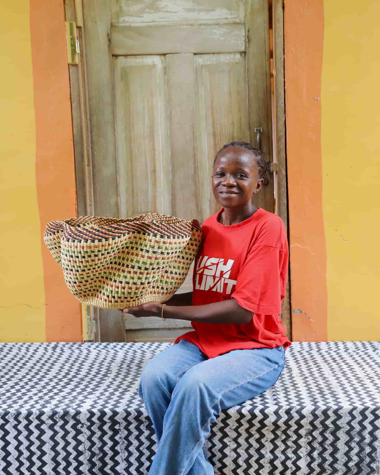 Woman holding large Pakurigo Wave Décor Basket in dark straw with amber, red and green check pattern