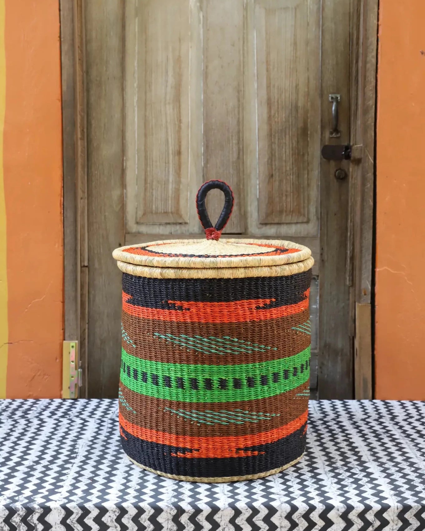 Lidded Laundry Basket with coil (Small) by The Baba Tree. Handwoven elephant grass with leather handle. Premium Bolgatanga artisan decor.