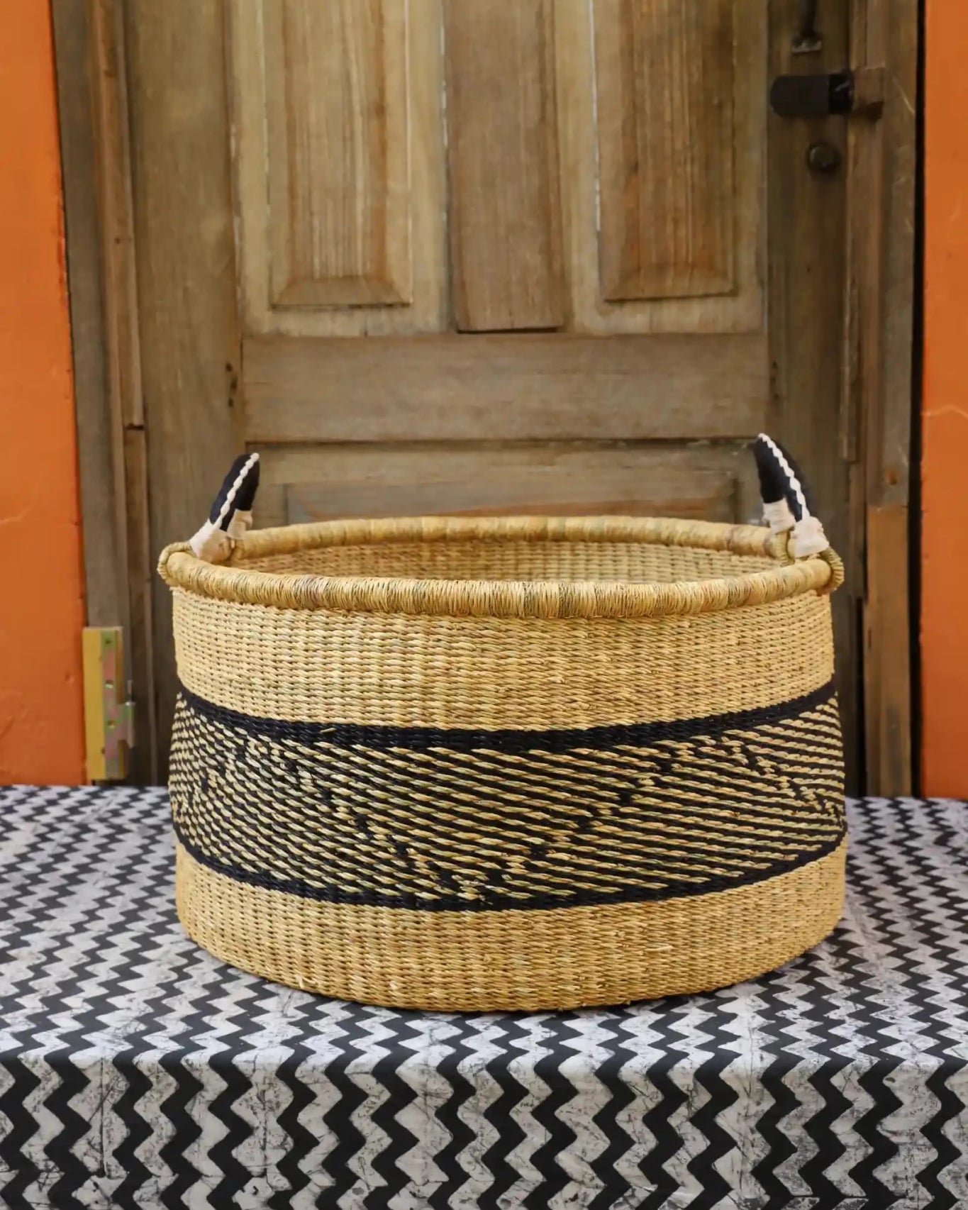 Woven Tub (Large) handwoven in Ghana sitting on black and white cloth with wooden door background