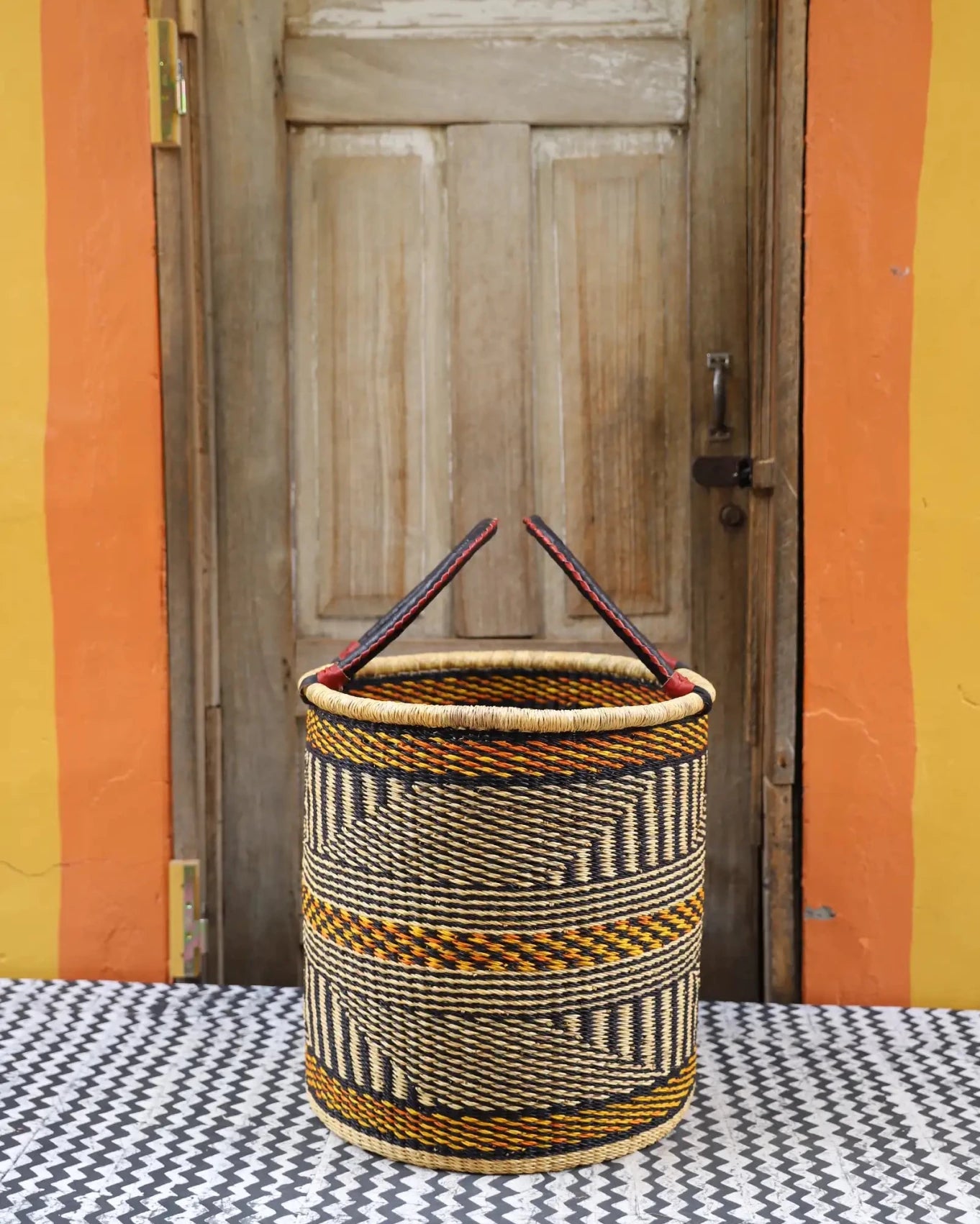 Open Laundry Basket (Medium) by The Baba Tree. Handwoven elephant grass storage with leather handles. Bolgatanga artisan decor.