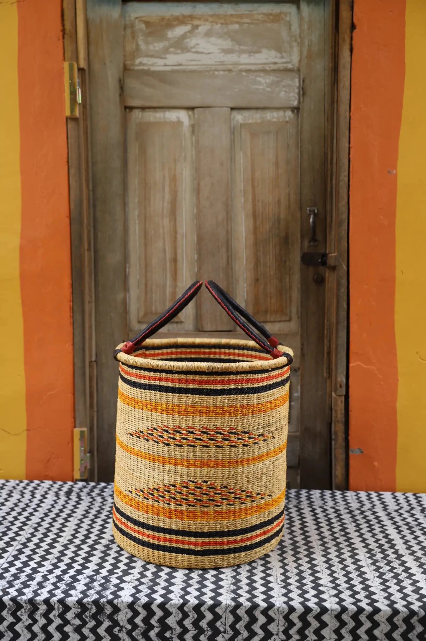 Open Laundry Basket (Medium) by The Baba Tree. Handwoven elephant grass storage with leather handles. Bolgatanga artisan decor.
