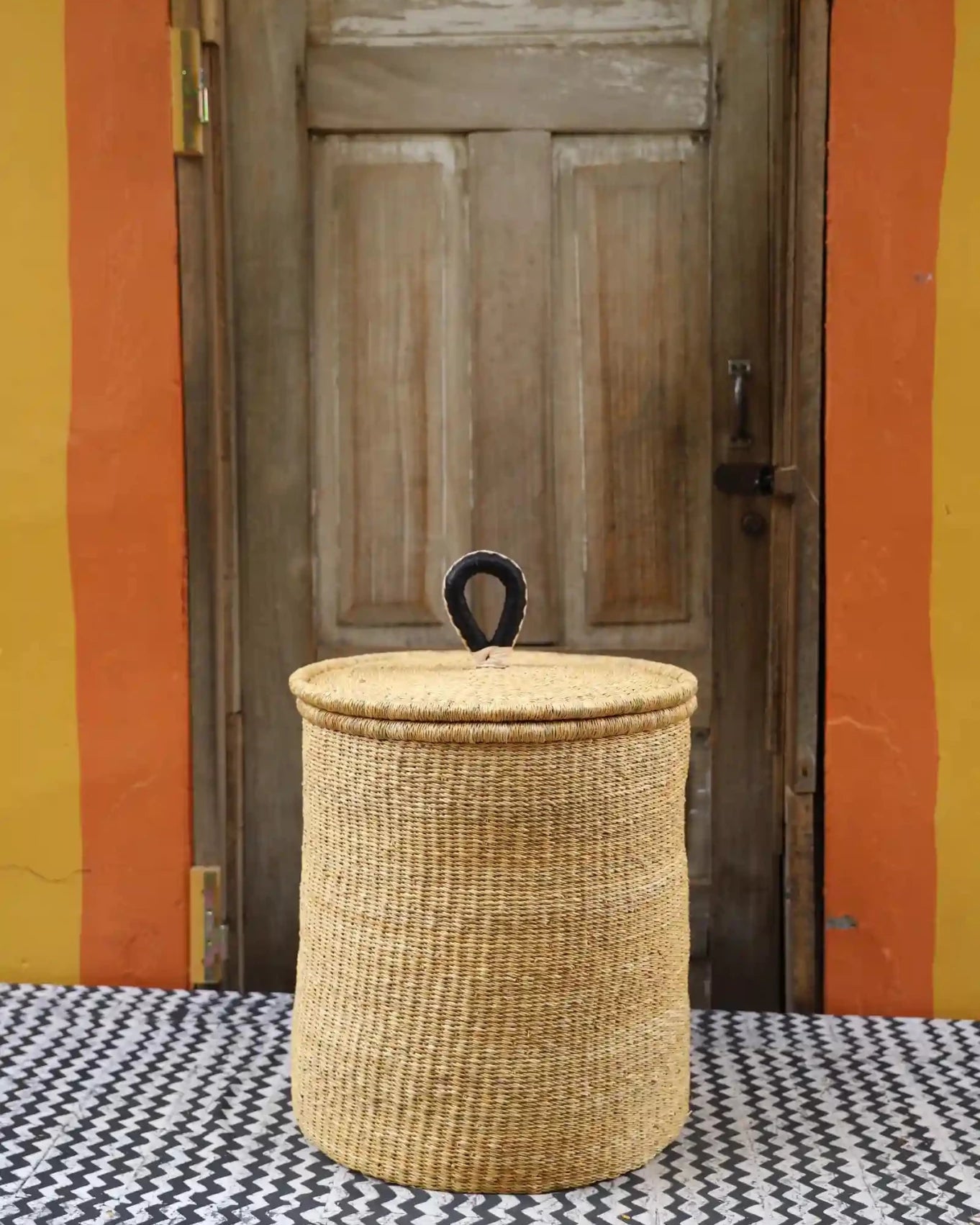 Lidded Laundry Basket with coil (Medium) by The Baba Tree. Handwoven elephant grass with leather handle. Premium Bolgatanga artisan decor.