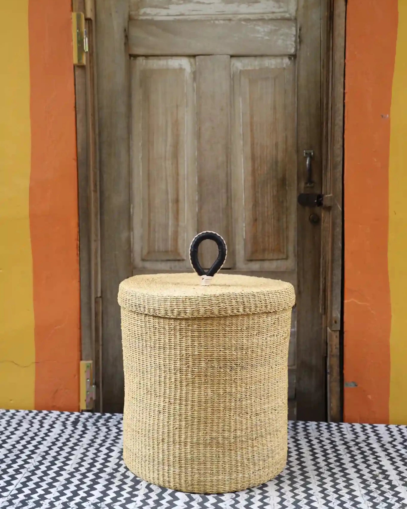 Lidded Laundry Basket (Medium) by The Baba Tree. Handwoven elephant grass with leather handle. Premium Bolgatanga artisan decor.l