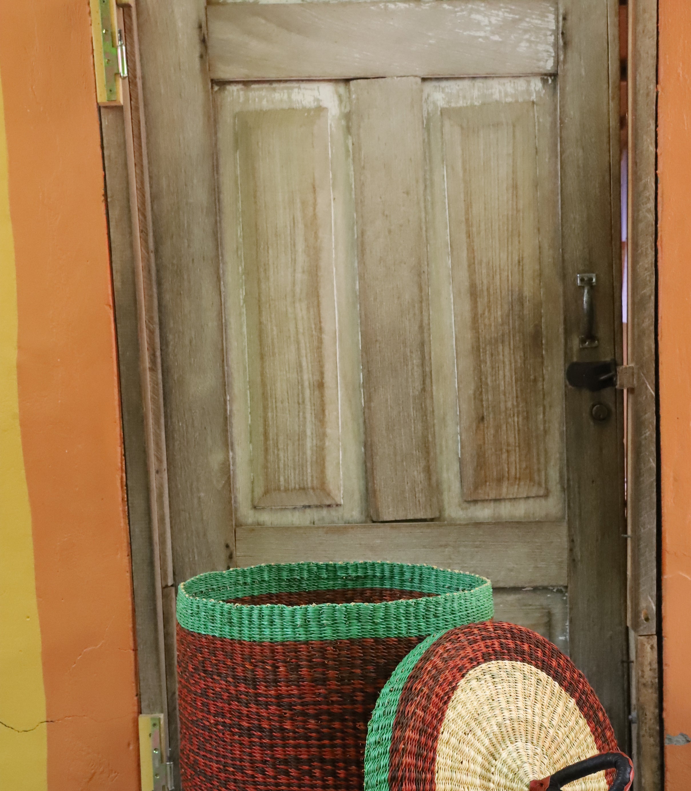 Lidded laundry basket in solid rust-red weave, lid resting alongside showing the straw underside.