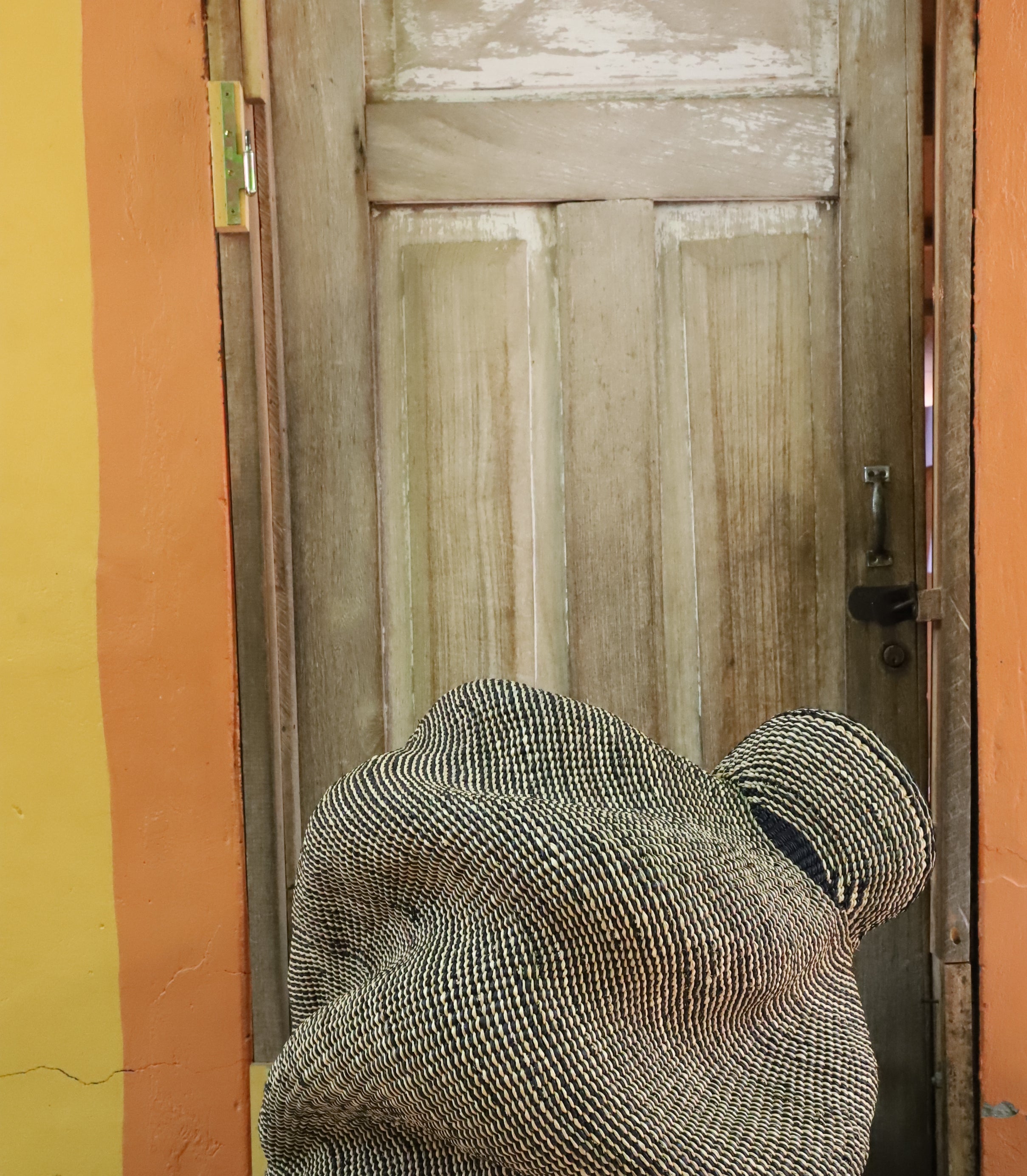 Spiral-form Bolga basket in natural straw, side view showing the curved tail detail.