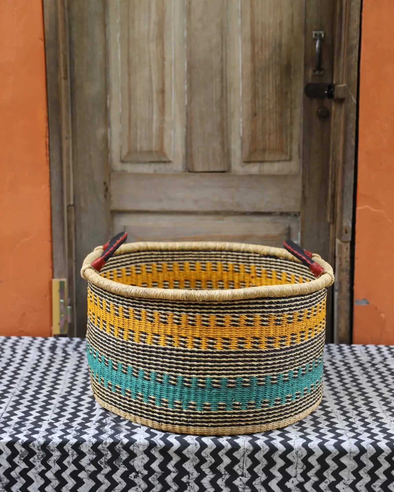 Woven Tub (Large) handwoven in Ghana sitting on black and white cloth with wooden door background