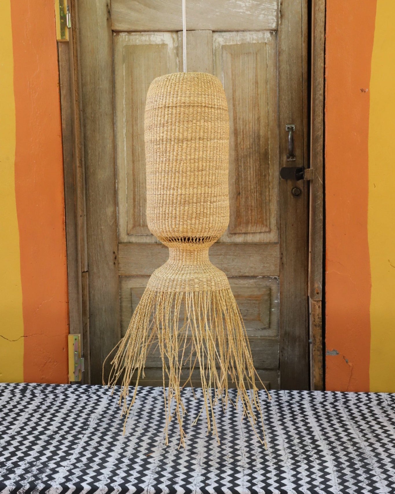 Woven basket hanging against a wooden door with colorful striped background